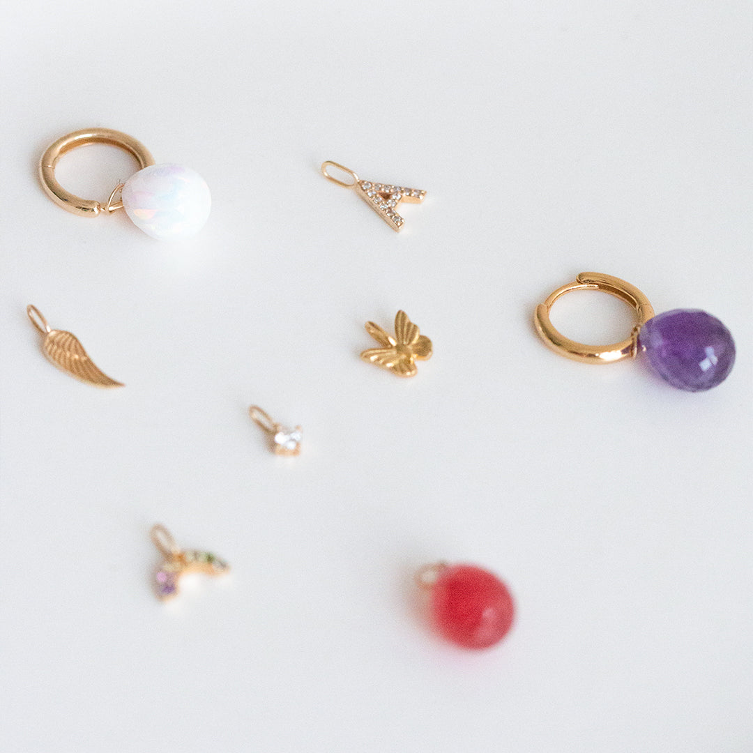 Assorted gold charms including crystals, letter, and symbols